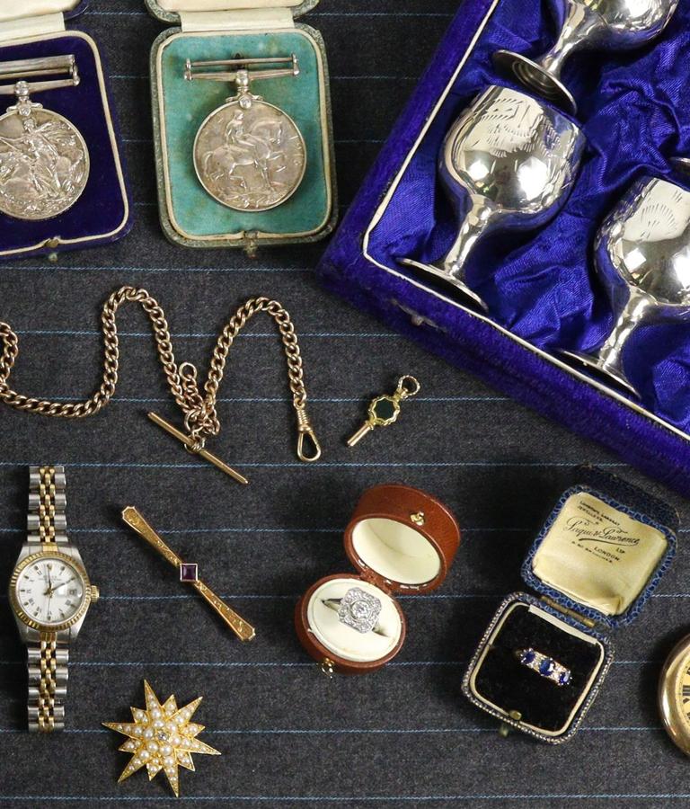 Medals, a wristwatch, rings in their boxes and gold chains laid out for valuation