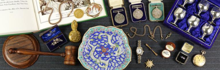 Medals, silver, porcelain and a pocket watch laid out for valuation